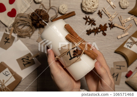 Unrecognizable young woman paint numbers on candles. Female making homemade advent calendar Made with your own hands step by step DIY crafts do it yourself. Preparation to christmas concept. Seasonal 106571468
