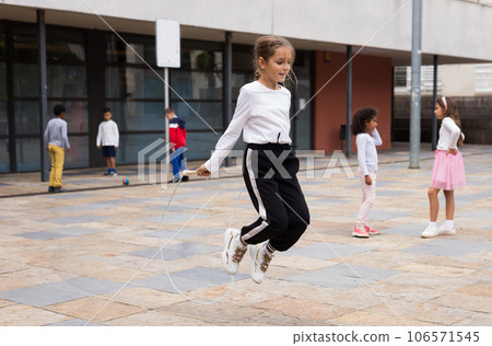 Sporty tween girl jumping rope in school yard during recess Sporty tween girl jumping rope in school yard during recess 106571545