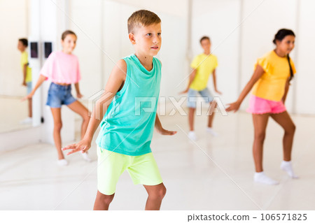 Concentrated tween boy learning charleston during group dance class Concentrated tween boy learning charleston during group dance class 106571825