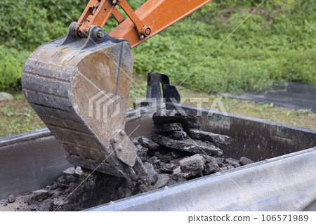 路面工程挖掘機將拆除的舊瀝青裝載到卡車上的圖片 106571989