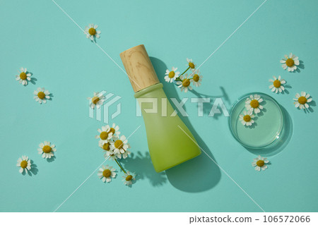 View from above of cosmetic bottle displayed with glass petri dish containing transparent fluid with fresh flowers. Cosmetics, products for care and personal hygiene concept View from above of cosmetic bottle displayed with glass petri dish containing transparent fluid with fresh flowers. Cosmetics, products for care and personal hygiene concept 106572066