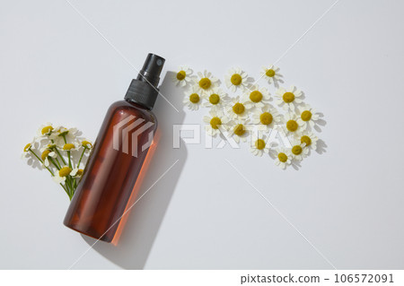 Many white flowers arranged with unbranded spray bottle. Chamomilla (Matricaria chamomilla) is a common ingredient in products that address a variety of skin conditions 106572091