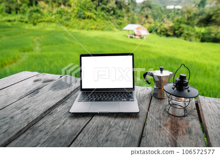 Laptop computer blank screen on a wooden terrace in the background of rice fields Laptop computer blank screen on a wooden terrace in the background of rice fields 106572577