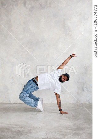 Man dancing break dance against background of gray wall in studio. Cool guy dancer, copy space Man dancing break dance against background of gray wall in studio. Cool guy dancer, copy space 106574772