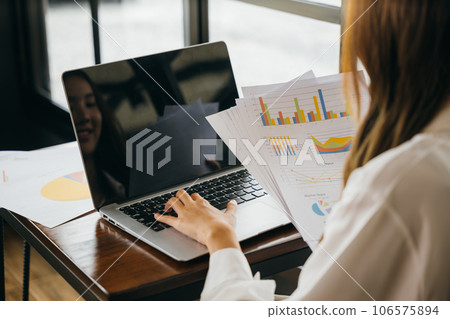 Businesswoman working and comparing forecasting and graphic documents paperwork with laptop computer, Happy female holding papers review report analyzing work results on graph chart outside office Businesswoman working and comparing forecasting and graphic documents paperwork with laptop computer, Happy female holding papers review report analyzing work results on graph chart outside office 106575894