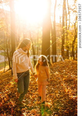 Portrait of happy mother and daughter in autumn forest at sunset. . Autumn women. 106575957
