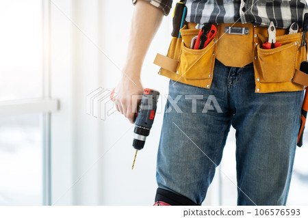 Worker wearing tool belt and holding drill Worker wearing tool belt and holding drill 106576593