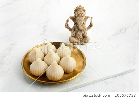 Idol of lord Ganesha with Modak Sweet Dish and flower. Ganesh chaturthi Idol of lord Ganesha with Modak Sweet Dish and flower. Ganesh chaturthi 106576738