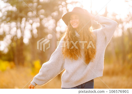 Stylish woman in sweater and hat enjoys autumn nature. People, freedom, lifestyle, travel concept. Stylish woman in sweater and hat enjoys autumn nature. People, freedom, lifestyle, travel concept. 106576901