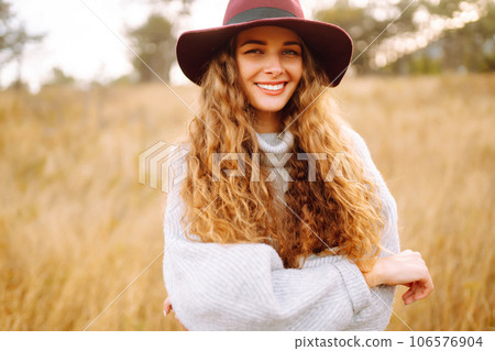 Stylish woman in sweater and hat enjoys autumn nature. People, freedom, lifestyle, travel concept. Stylish woman in sweater and hat enjoys autumn nature. People, freedom, lifestyle, travel concept. 106576904
