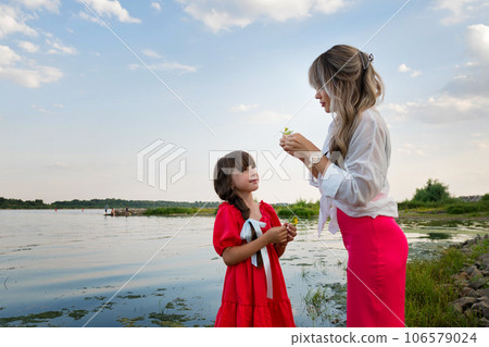 Mom and little daughter walking by the lake or pond 106579024