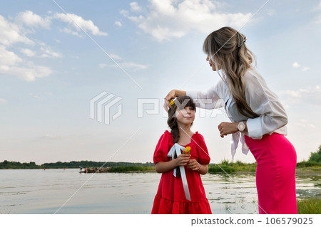 Mom and little daughter walking by the lake or pond Mom and little daughter walking by the lake or pond 106579025