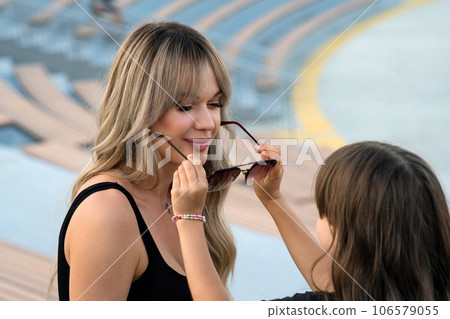 Little girl helps mom to put on sunglasses on walk 106579055