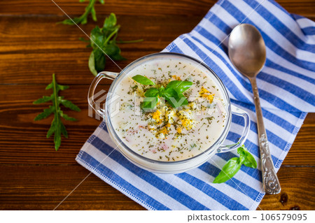 Cold soup with cucumbers, eggs, vegetables, yogurt and fresh herbs in a glass bowl . Cold soup with cucumbers, eggs, vegetables, yogurt and fresh herbs in a glass bowl . 106579095