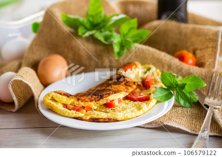 Stuffed omelette with tomatoes on a light wooden background. Stuffed omelette with tomatoes on a light wooden background. 106579122