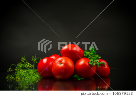 Ripe red tomatoes with greens on black background. Ripe red tomatoes with greens on black background. 106579138