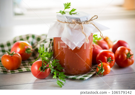 Cooked homemade tomato juice canned in a jar of natural tomatoes. 106579142