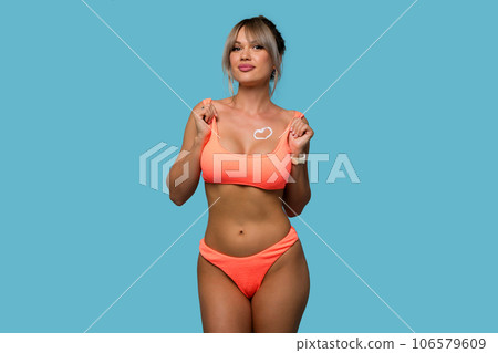 Woman with sunscreen on tanned breast in form of heart 106579609