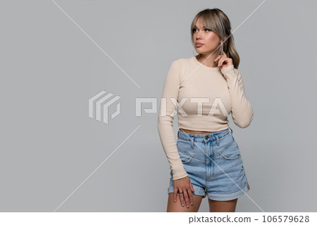 Woman in beige long sleeve and shorts on light background Woman in beige long sleeve and shorts on light background 106579628