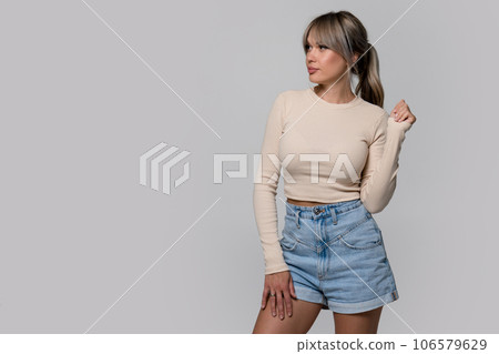 Woman in beige long sleeve and shorts on light background Woman in beige long sleeve and shorts on light background 106579629