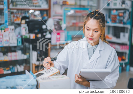 Pharmacist checking Checks Inventory of Medicine, Drugs, Vitamins with tablet and checking patient's prescription in modern pharmacy. 106580683