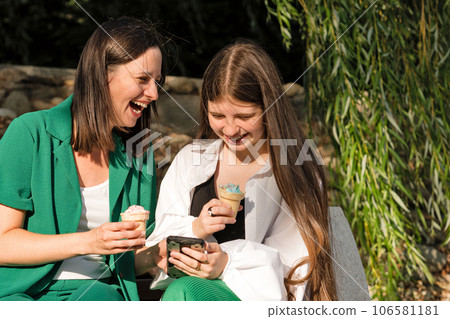 Mom and teenage daughter eat ice cream on walk Mom and teenage daughter eat ice cream on walk 106581181