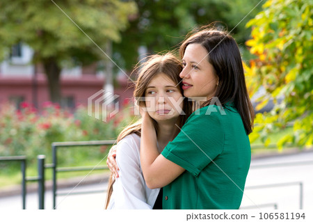 Mom and teenage daughter hugging on walk in park 106581194