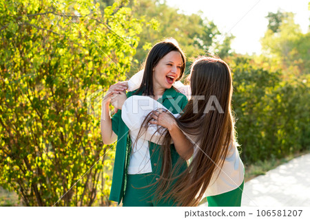 Mom and teenage daughter hugging on walk in park Mom and teenage daughter hugging on walk in park 106581207