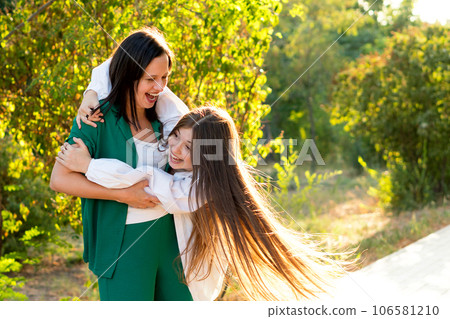 Mom and teenage daughter hugging on walk in park 106581210