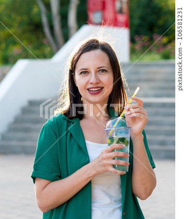 Woman drink soft drink on walk in park 106581231