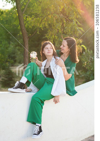 Mom and teenage daughter drink soft drinks on walk Mom and teenage daughter drink soft drinks on walk 106581238