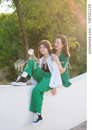 Mom and teenage daughter drink soft drinks on walk 106581239