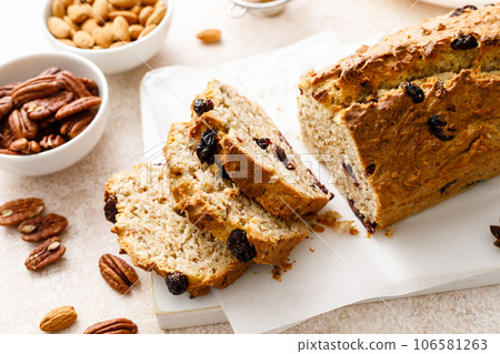 Fruitcake with cranberry, almond and pecan nuts sliced on a wooden board 106581263