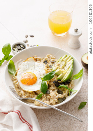 Savory oatmeal with fried sunny side up egg, avocado and pumpkin seeds for healthy breakfast Savory oatmeal with fried sunny side up egg, avocado and pumpkin seeds for healthy breakfast 106581306