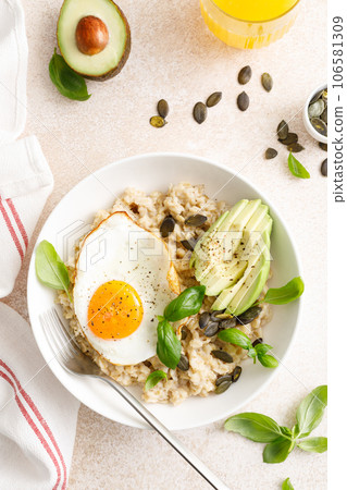 Savory oatmeal with fried sunny side up egg, avocado and pumpkin seeds for healthy breakfast 106581309