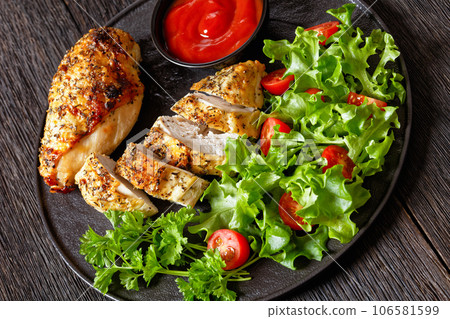 Baked Split Chicken Breasts with salad on plate 106581599