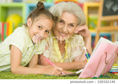 Portrait of a cute little girl drawing with her grandmother 106582146