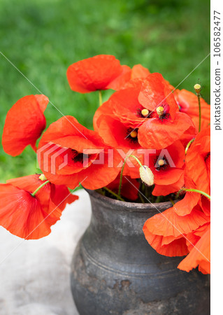 Bouquet of wild flowers of red poppies in an old clay jug. Summer photo, rustic style, close-up. 106582477