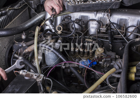 Car engine repair. Diesel engine services. Hands with a mechanic with a wrench repair Mercedes parts. 106582600