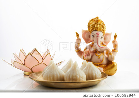 Idol of lord Ganesha with Modak Sweet Dish and flower. Ganesh chaturthi Idol of lord Ganesha with Modak Sweet Dish and flower. Ganesh chaturthi 106582944