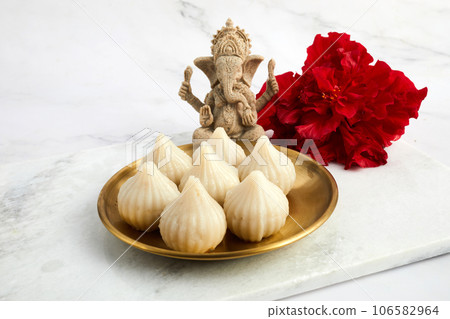 Idol of lord Ganesha with Modak Sweet Dish and flower. Ganesh chaturthi Idol of lord Ganesha with Modak Sweet Dish and flower. Ganesh chaturthi 106582964