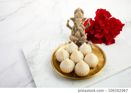 Idol of lord Ganesha with Modak Sweet Dish and flower. Ganesh chaturthi 106582967