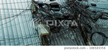 Tangled electrical wires and tangled communication lines on urban electric poles create a chaotic network. Disorganized and messy to organization management concept. Should take underground wire. 106583358