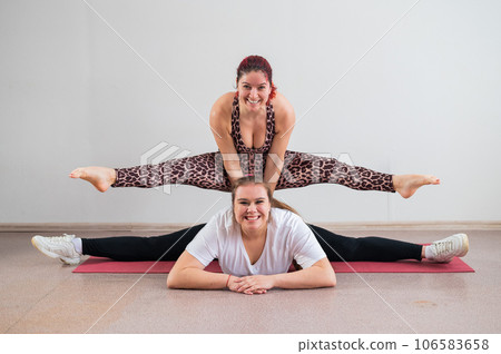 Caucasian woman doing a handstand on her friend. Pair acrobatics. Caucasian woman doing a handstand on her friend. Pair acrobatics. 106583658