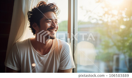 早晨陽光照進來的窗邊，一個年輕人燦爛地微笑著 106583889