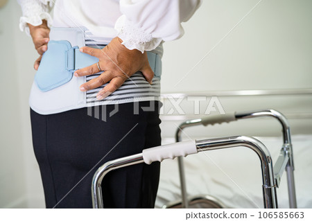 Asian lady patient wearing back pain support belt for orthopedic lumbar with walker. 106585663