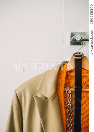 Capsule Wardrobe Autumn 2023, What To Wear This Fall. Autumn fall minimalist wardrobe with orange warm knitted sweater on wooden clothes hanger. Autumn capsule, warm fashion trends 106586540