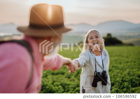 Senior couple standing in the middle of meadow and holding hands. 106586592