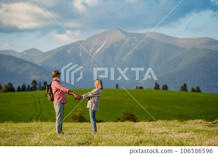Senior couple standing in the middle of meadow and having romantic moment at the autumn nature. 106586596
