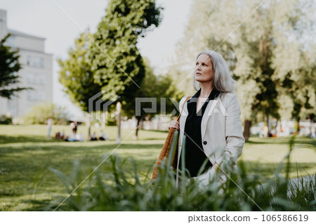 Portrait of beautiful female manager in middle age with gray hair walking through the city. 106586619